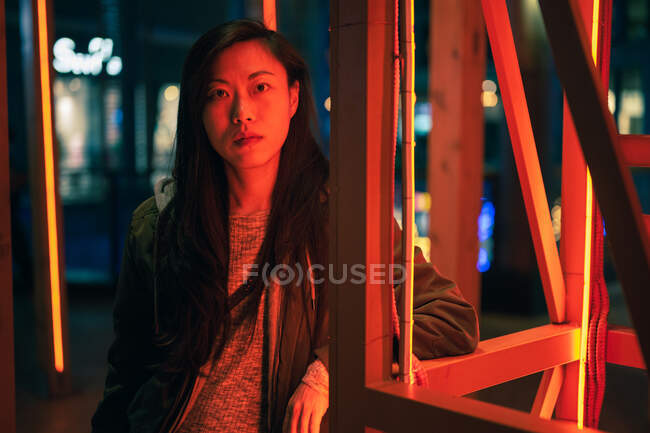 Retrato de menina asiática de pé perto de luz de néon à noite na rua — Fotografia de Stock