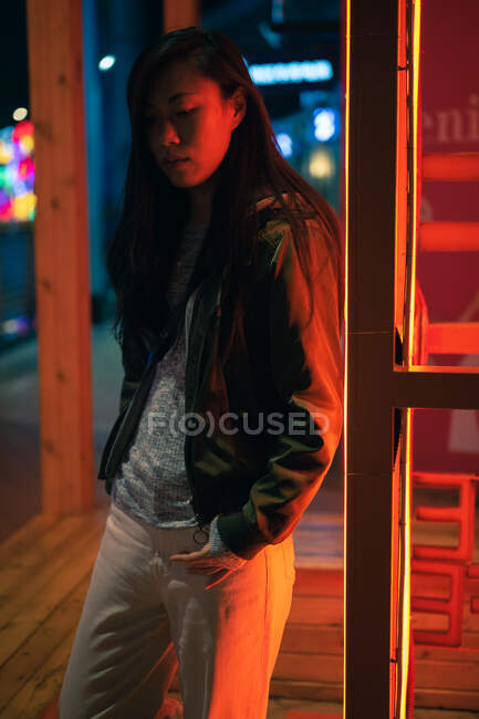 Retrato de chica asiática de pie cerca de la luz de neón en la noche en la calle - foto de stock
