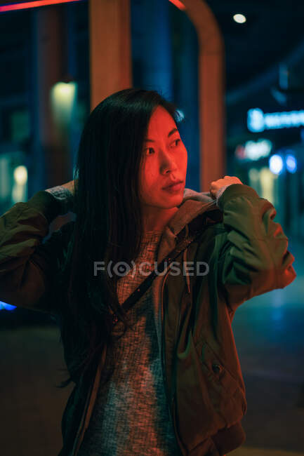 Портрет азіатської дівчинки, що стоїть біля неонового світла вночі на вулиці. — стокове фото