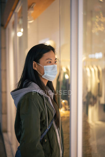 Side view asian girl wearing a mask in front of clothing shop — Stock Photo