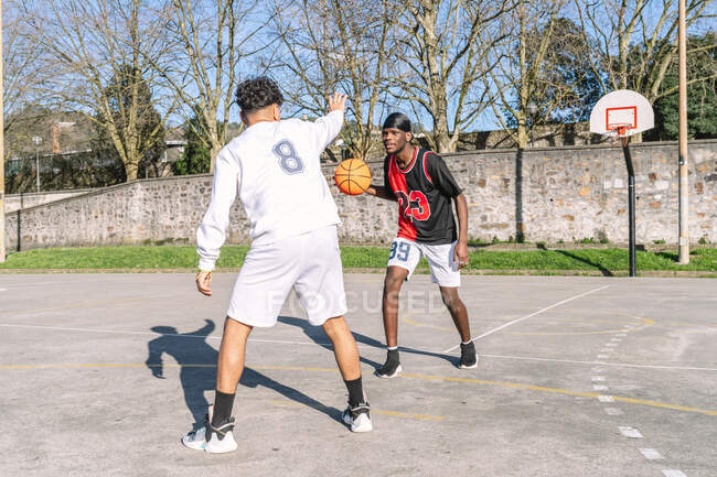 African American male and hispanic friend playing streetball — Stock Photo
