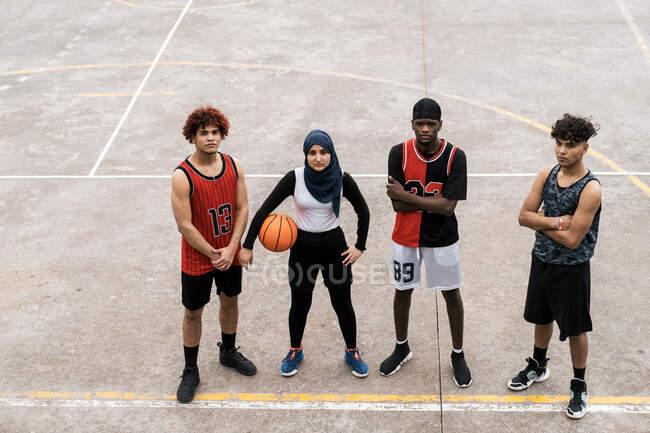 Von oben von entschlossenen verschiedenen Spielern der Streetball-Mannschaft, die zusammen auf dem Basketballplatz stehen und in die Kamera schauen — Stockfoto