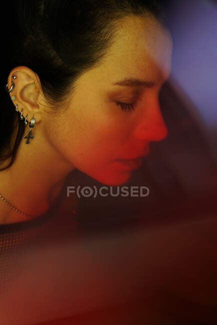 Side view of crop young tender female with closed eyes in earrings and chain — Stock Photo