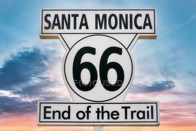 Angolo basso di cartello con iscrizione Santa Monica 66 Fine del sentiero sullo sfondo del cielo colorato tramonto — Foto stock