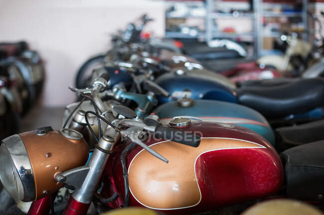 Molti vecchi modelli danneggiati motociclette arrugginite collocati in file in officina servizio di riparazione — Foto stock