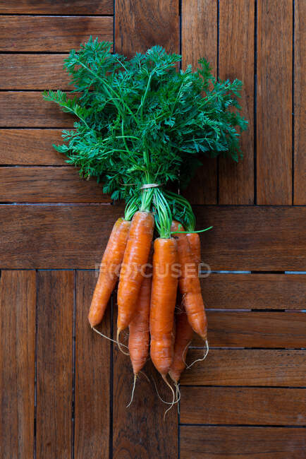From above of bunch of ripe carrots placed on black shabby background in studio — Stock Photo