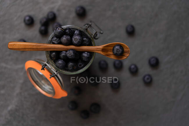 Fresh blueberries falling in glass jar and splashing water on gray background in studio — Stock Photo
