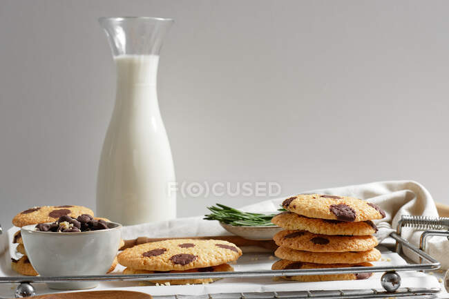 Leckere hausgemachte süße Kekse mit Schokoladenschiffen auf Tablett mit Glas Milch serviert — Stockfoto