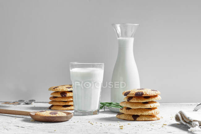 Leckere hausgemachte frisch gebackene Kekse mit Schokoladenchips serviert mit einem Glas Milch auf dem Tisch — Stockfoto