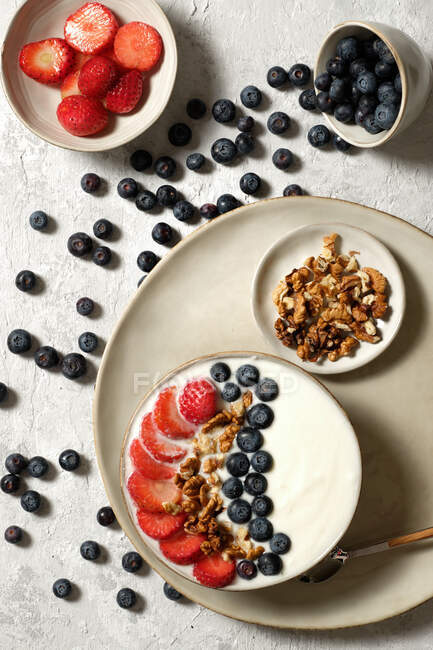 Верхний вид вкусной миски здорового завтрака с белым йогуртом и свежей клубникой и черникой с мюсли — стоковое фото