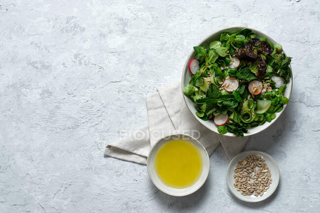 Top view of fresh healthy vegetable salad in bowl served on table with olive oil and sunflower seeds — Stock Photo