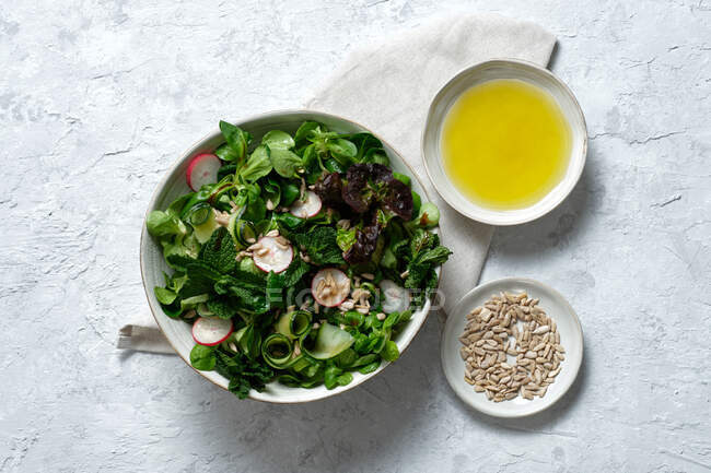 Draufsicht auf frischen, gesunden Gemüsesalat in Schüssel auf dem Tisch serviert mit Olivenöl und Sonnenblumenkernen — Stockfoto