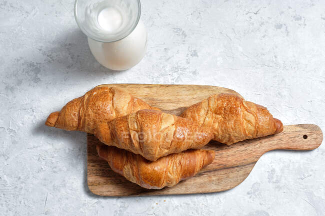 De cima deliciosos croissants e garrafa de leite colocado na mesa para o café da manhã na cozinha — Fotografia de Stock