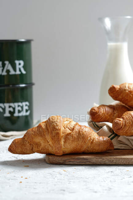 Delicious croissants and bottle of milk placed on table for breakfast in kitchen — Stock Photo