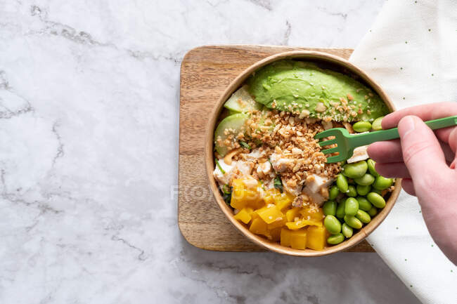 From above of anonymous crop person eating delicious homemade poke served on wooden board on table — Stock Photo