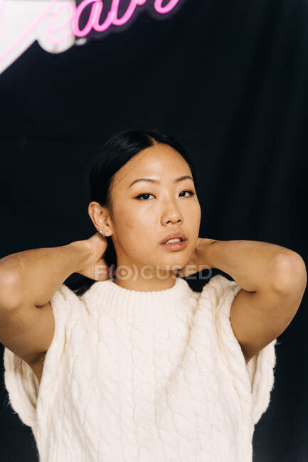Jovem étnico feminino sem emoção em vestuário casual em pé olhando para a câmera sob o título — Fotografia de Stock