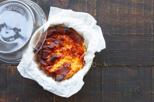 De arriba delicioso pastel de queso al horno servido en un recipiente en una mesa de madera - foto de stock