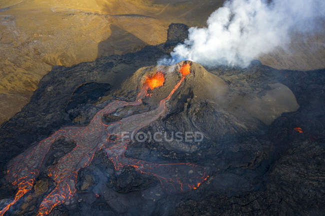 Desde arriba el magma sale del agujero del volcán y corre como ríos de lava sobre el suelo en Islandia - foto de stock