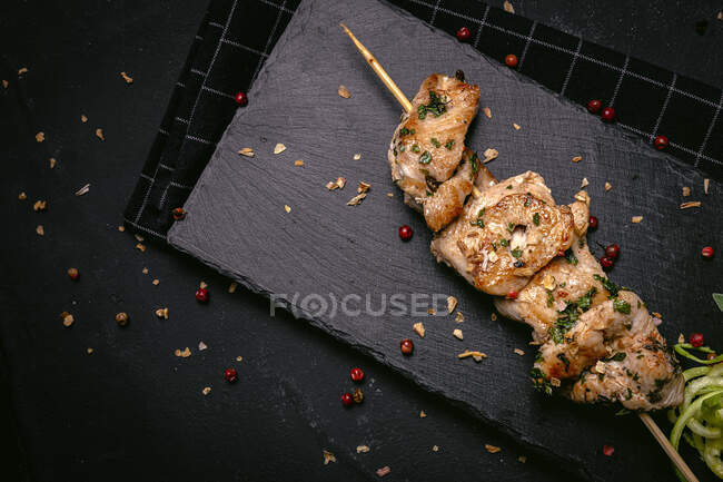 De dessus de viande fraîchement cuite appétissante sur brochette servie sur plateau sur table noire — Photo de stock