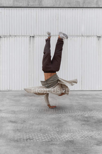 Ballerino maschile irriconoscibile che mostra movimento breakdance mentre si bilancia sulle braccia e si esibisce Luppolo a mano su terreno di cemento in area urbana — Foto stock