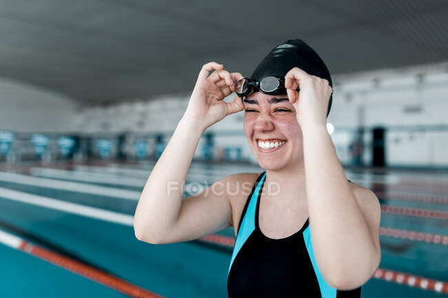 Mujer que se pone gafas de natación mientras se prepara para nadar - foto de stock