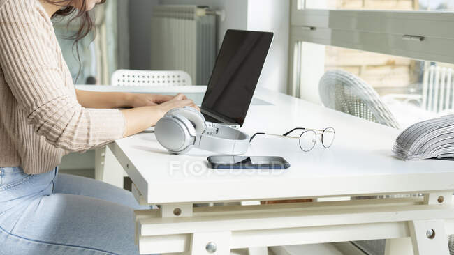 Cortar vista lateral feminino navegação internet no netbook à mesa no apartamento — Fotografia de Stock
