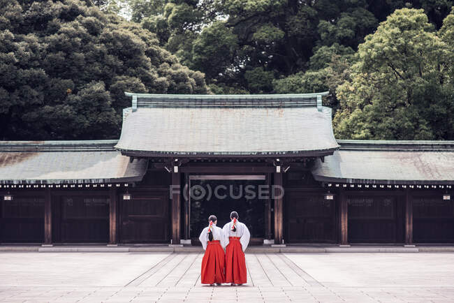 Погляд на нерозпізнаних людей у традиційному кімоно, що стоїть за стародавнім храмом Меїджі, розташованим у горах Шібуя (Токіо, Японія). — стокове фото