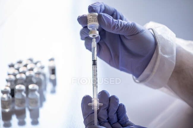 Anonymous female doctor with vaccine bottle and syringe — Stock Photo
