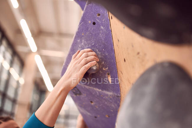 Crop anonymous female alpinist climbing artificial wall while practicing in bouldering club — Stock Photo