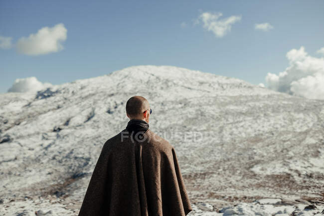 Blick zurück auf anonyme männliche Touristen im Kap, die den schneebedeckten Berg unter blauem wolkenverhangenem Himmel im Winter bewundern — Stockfoto