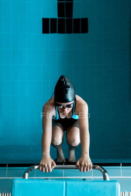 Woman with hands on a ladder inside the pool ready to swim — Stock Photo