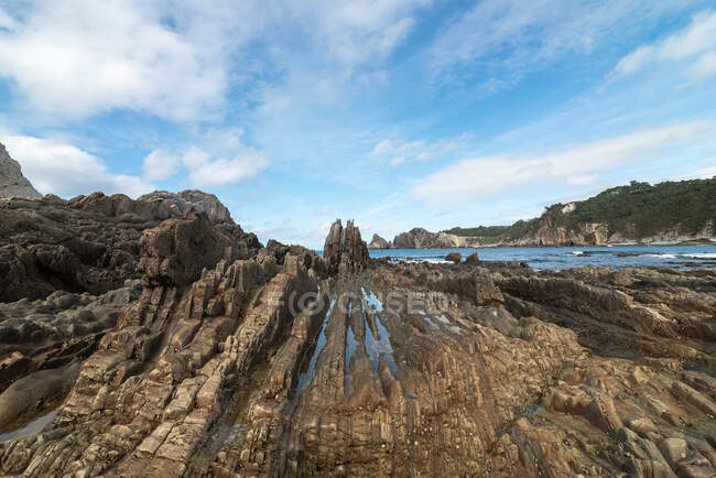 Vue panoramique de formations rocheuses sur la plage de Gueirua près de la mer calme sous le ciel bleu des Asturies — Photo de stock