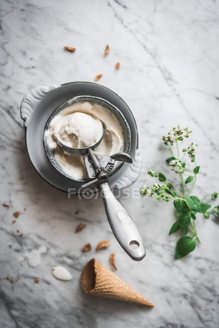 Du dessus du cône de gaufre près des cuillères de glace de lait meringue et des feuilles de menthe fraîche sur la table en marbre — Photo de stock