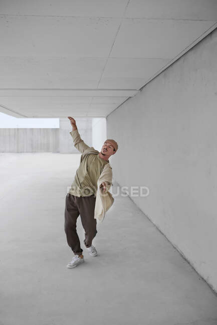 Талантливый мужчина танцует брейк-данс в просторном переходе в городской местности — стоковое фото