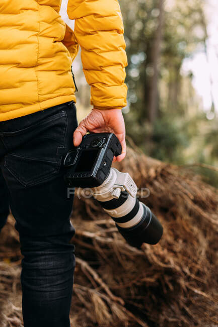 Rückansicht eines anonymen Fotografen, der seine Kamera mit verschwommenem Hintergrund in den Berg hält — Stockfoto