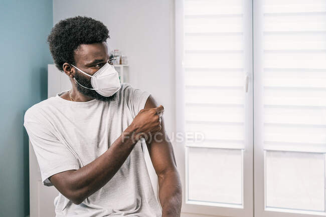 African American man patient holding cotton with alcohol disinfecting arm after covid vaccine procedure in clinic during coronavirus outbreak — Stock Photo