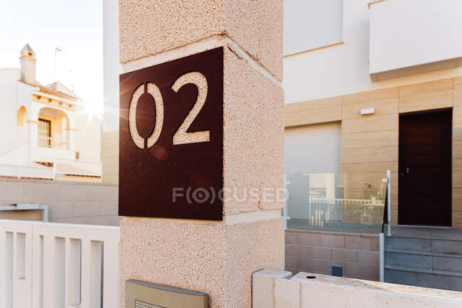 Numbers on post against contemporary house exteriors with entrance door and staircase in city on sunny day — Stock Photo