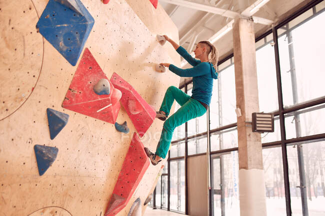 Sportlerin klettert beim Bouldertraining in professionellem Fitnessstudio auf künstliche Wand — Stockfoto