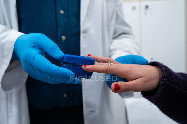 Crop médico irreconhecível usando oxímetro de pulso no dedo do paciente para examinar os sintomas de COVID 19 no hospital — Fotografia de Stock