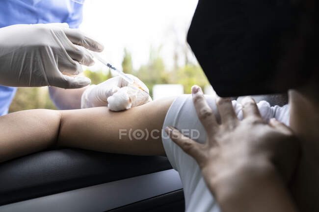 Обрезанная неузнаваемая медсестра в латексных перчатках и однородная вакцинация афроамериканской пациентки внутри автомобиля во время проезда через мобильную клинику во время вспышки коронавируса — стоковое фото