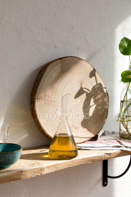 Vaso di vetro con olio aromatico naturale posto sullo scaffale in cucina casalinga — Foto stock