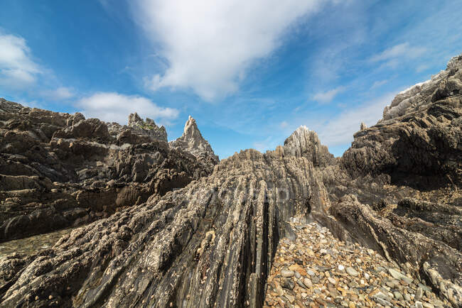 Scenic view of rocky formations on Gueirua beach near calm sea under blue sky in Asturias — Stock Photo