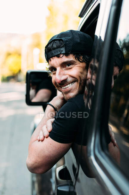Vista lateral do motorista do veículo off-road feliz inclinando-se para fora da janela e olhando para a câmera — Fotografia de Stock