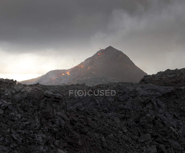 Боковой вид магмы искрит из вулканической ямы и течет как реки лавы по земле в Исландии — стоковое фото