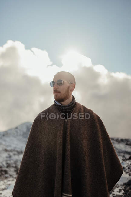 Турист на мисі захоплюється засніженою горою під блакитним хмарним небом взимку — стокове фото