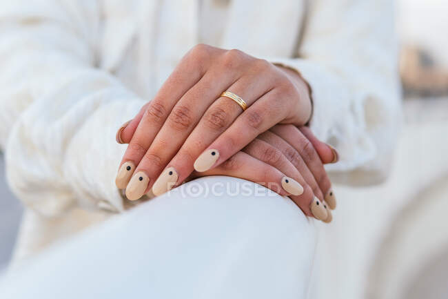 Crop unrecognizable bride with manicured nails and in golden wedding ring leaning on white railing — Stock Photo