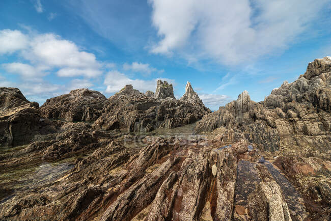 Vista panoramica delle formazioni rocciose sulla spiaggia di Gueirua vicino al mare calmo sotto il cielo blu nelle Asturie — Foto stock