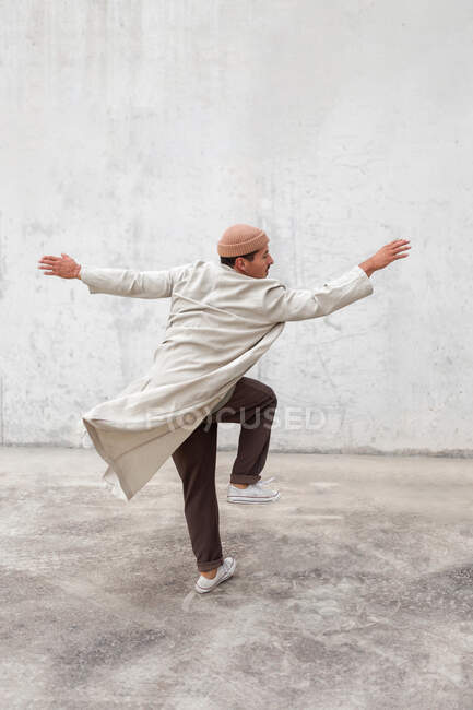 Back view of anonymous male break dancer performing in urban area near gray wall of building — Stock Photo