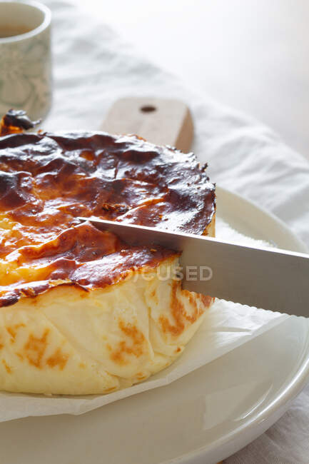 Cropped unrecognizable person slicing delicious baked cheesecake with knife served on a plate — Stock Photo