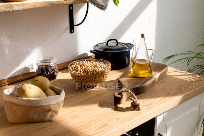 Ingredientes variados e utensílios colocados em mesa de madeira durante o processo de cozimento em casa cozinha com parede branca e interior minimalista em estilo ecológico natural — Fotografia de Stock